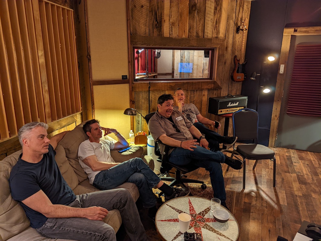 Four of five band members listening to takes